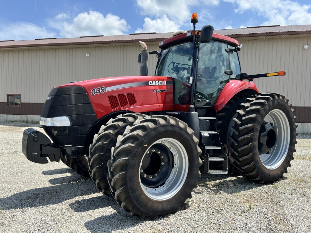 Red Case IH 335 tractor with large tires at auction site.