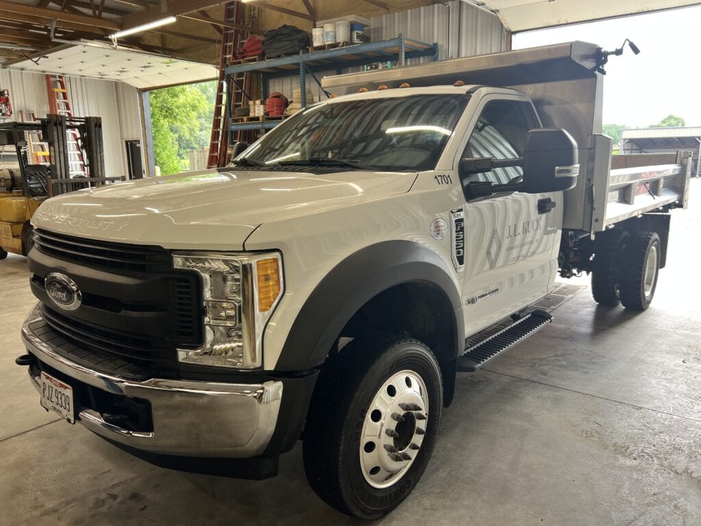 White Ford F-450 service truck with flatbed in garage.