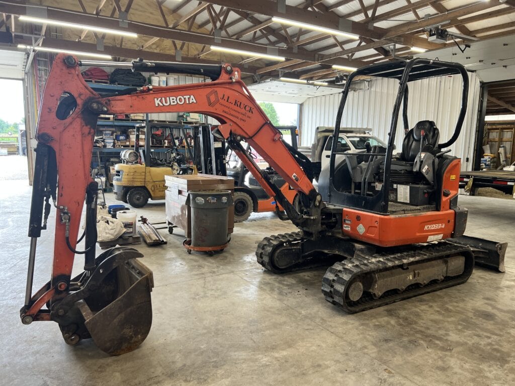 Orange Kubota mini excavator with black tracks inside a warehouse.
