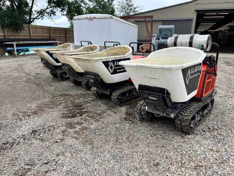 Two mini excavators with tracked wheels at an outdoor auction site.