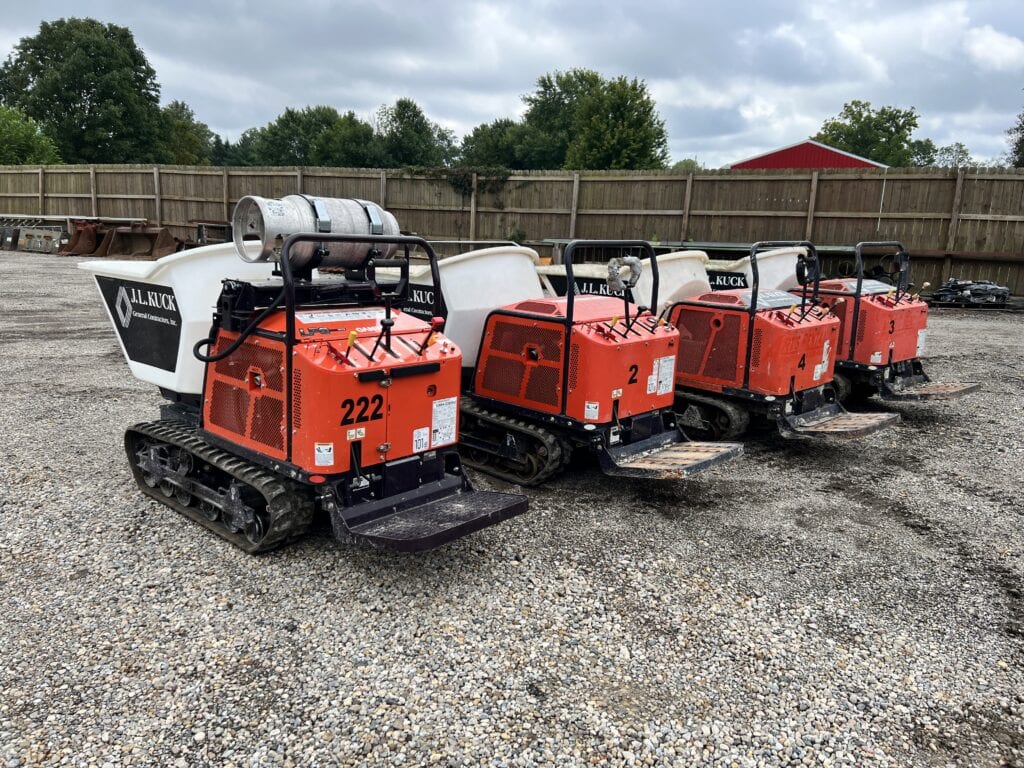 Three mini track loaders lined up at an auction site.