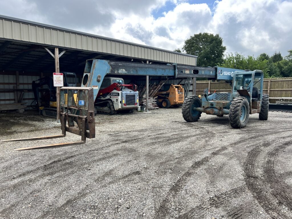 Construction machinery including a crane and forklift at auction yard.