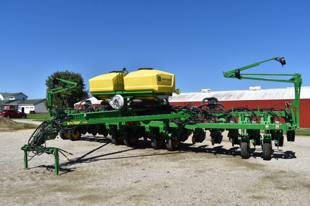 Green and yellow John Deere farming equipment on display outdoors.