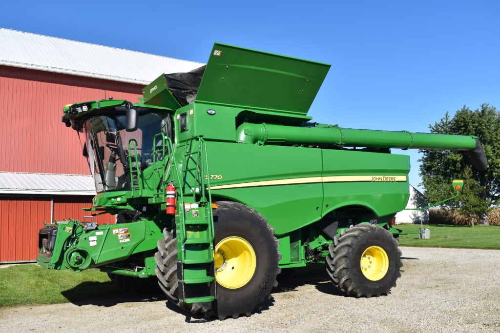 Green John Deere S770 combine harvester at a farm.