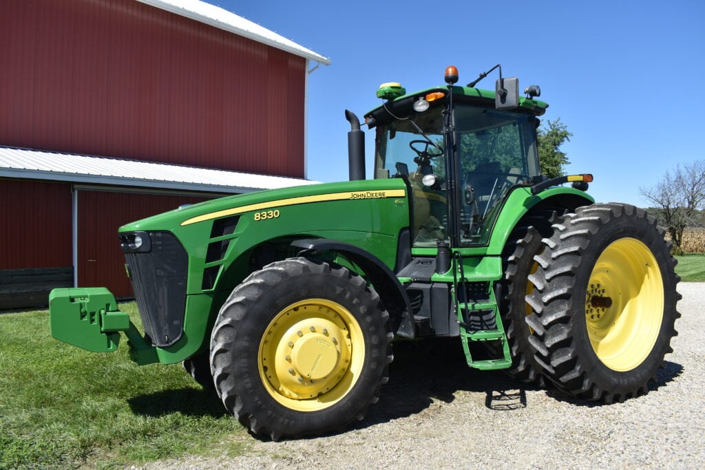 Green John Deere 8330 tractor with large tires at auction event.