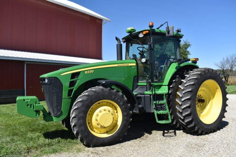 Green John Deere 8330 tractor with large tires at auction event.