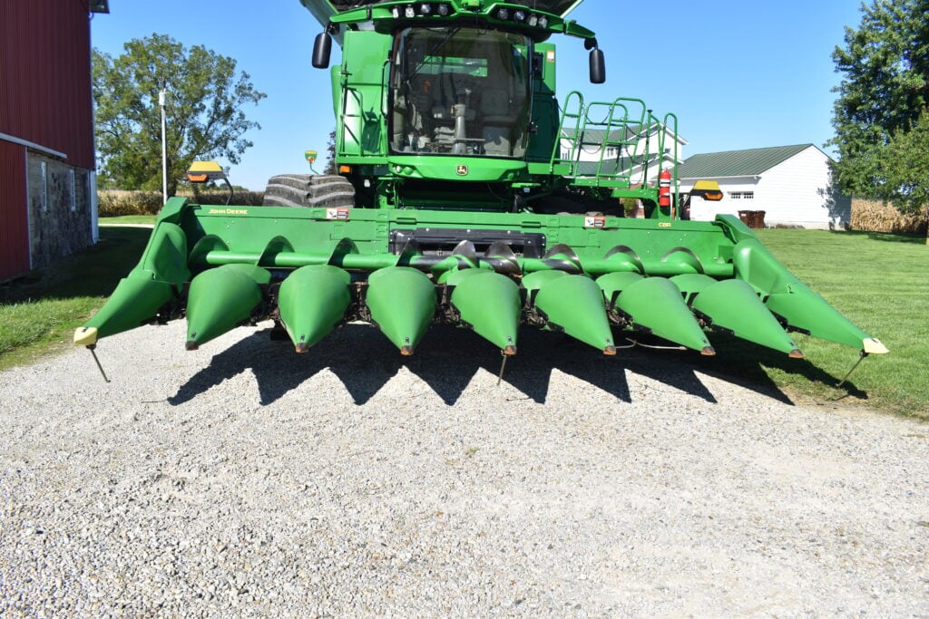 Large green harvesting machine with multiple cones for crop collection.
