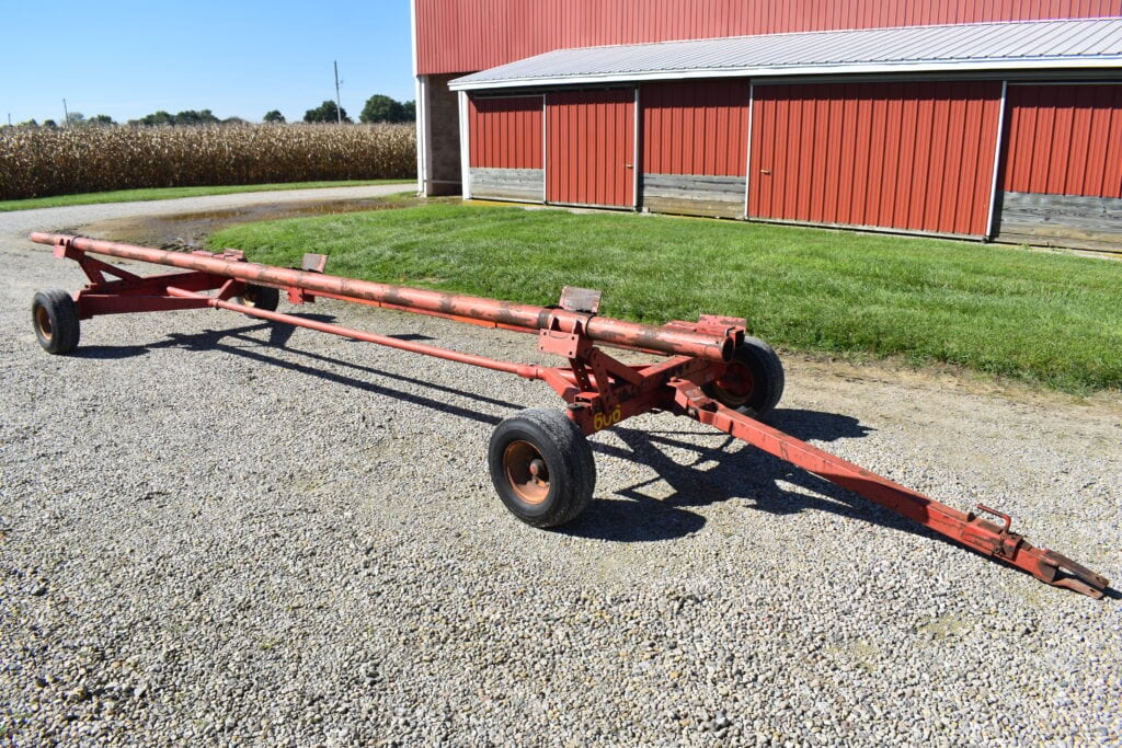 Red farm wagon on gravel with barn in background.