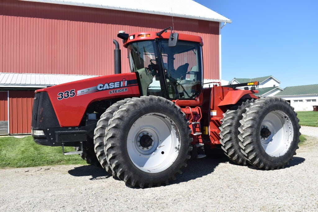 Red Case IH Steiger 335 tractor with large tires at auction site.