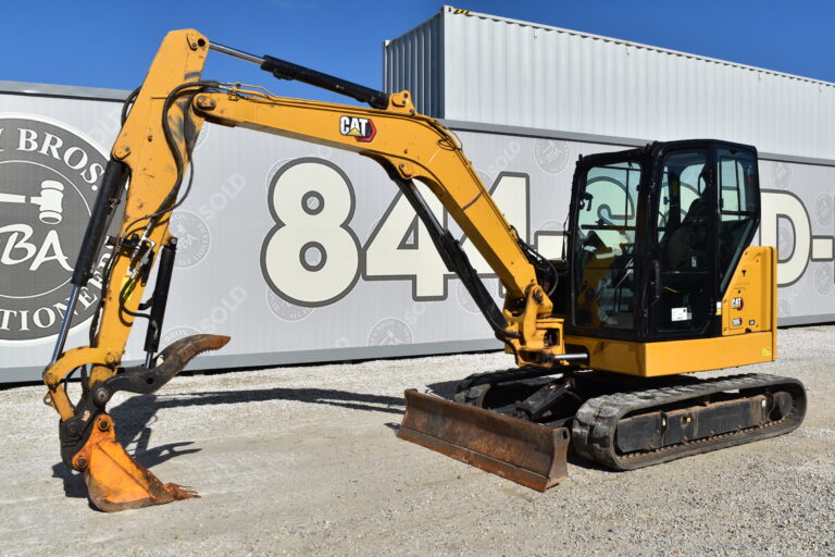 Yellow CAT mini excavator with digging arm and blade at Bussey Bros Auctioneers.