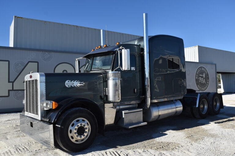 Black semi-truck parked outside with clear blue sky.