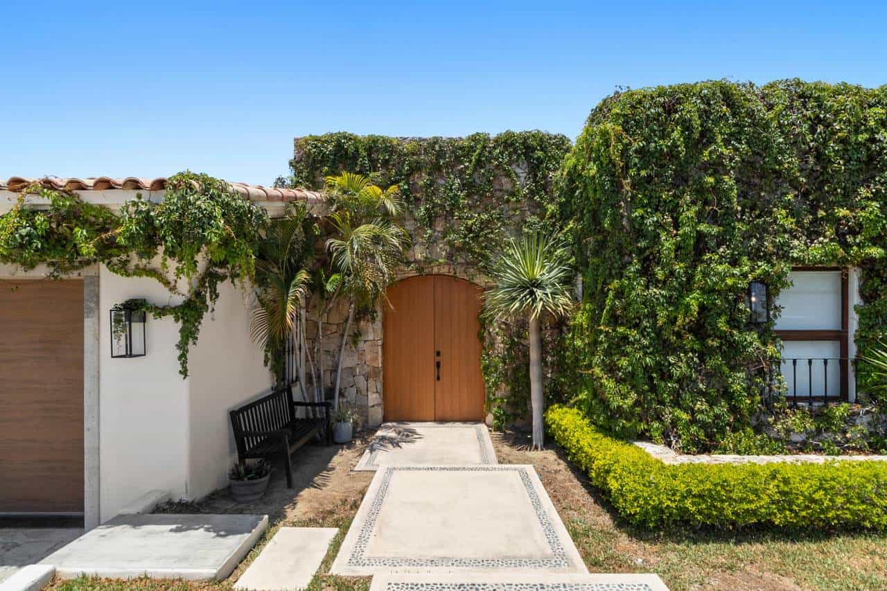 Cabo Del Sol Villa Entrance With Lush Greenery And Wooden Door, Ocean Views Nearby.