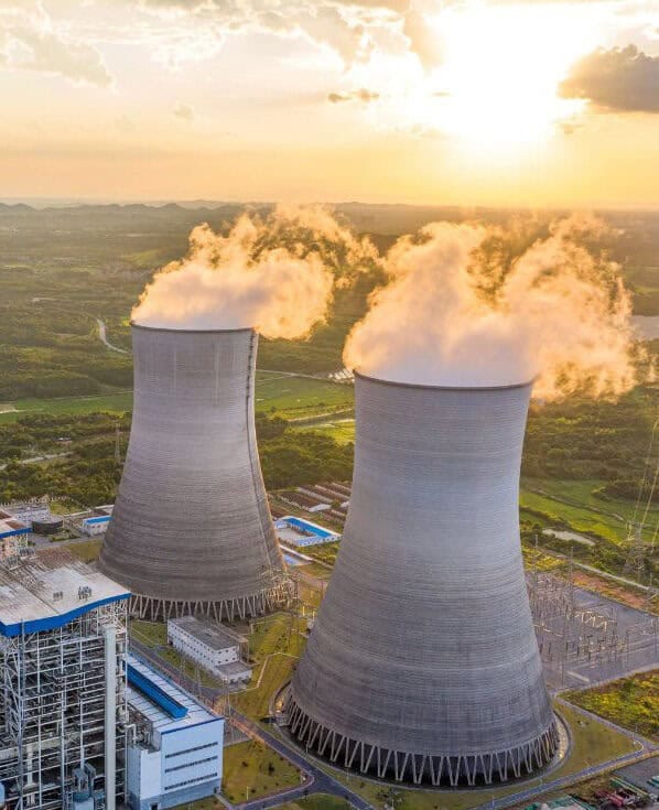 Luftaufnahme eines konventionellen Heizkraftwerks mit dampfenden Kühltürmen – Sinnbild für die notwendige Wärmewende in der Energiewirtschaft