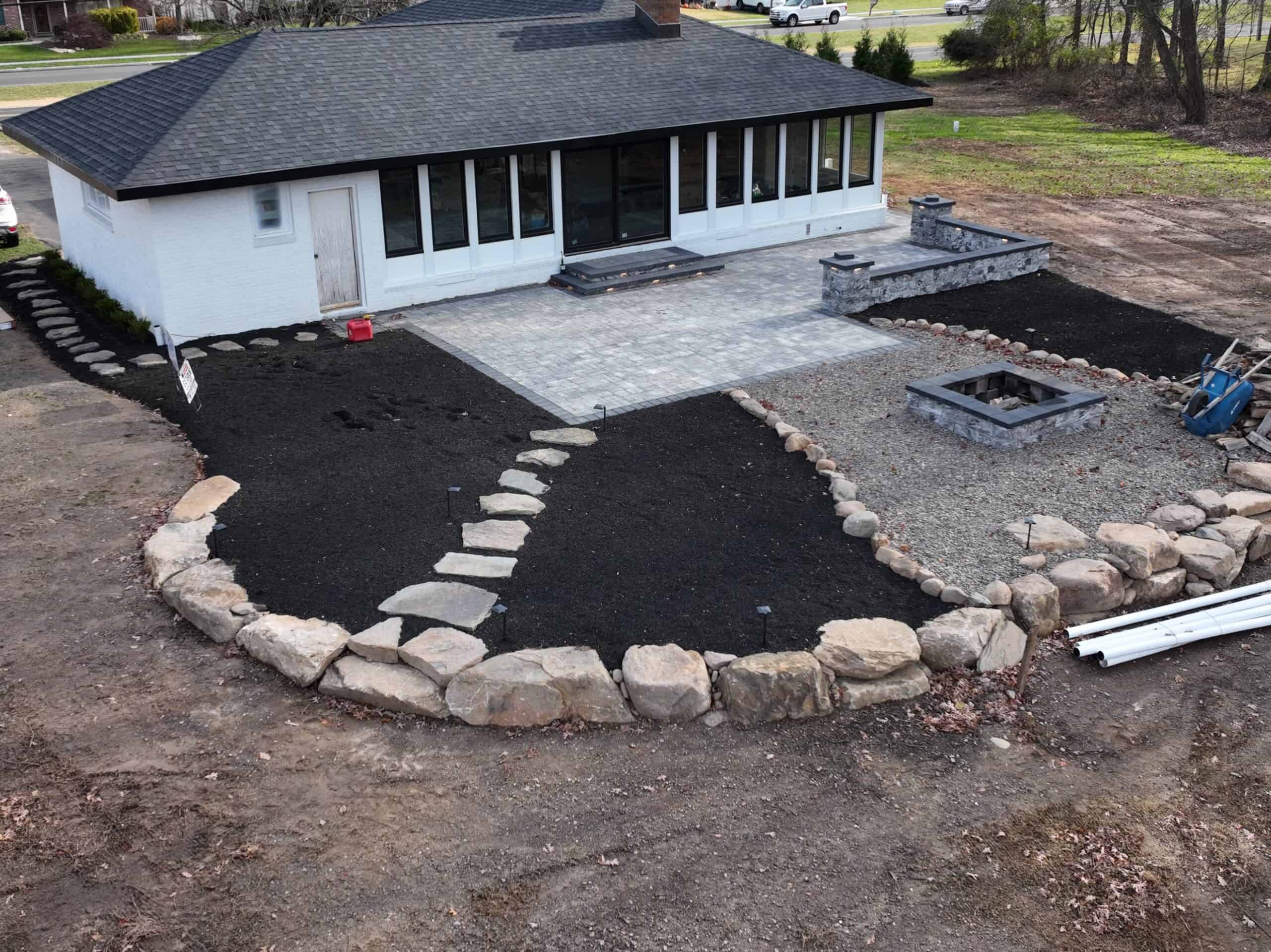 New landscaped backyard with stone border and paved patio under construction.