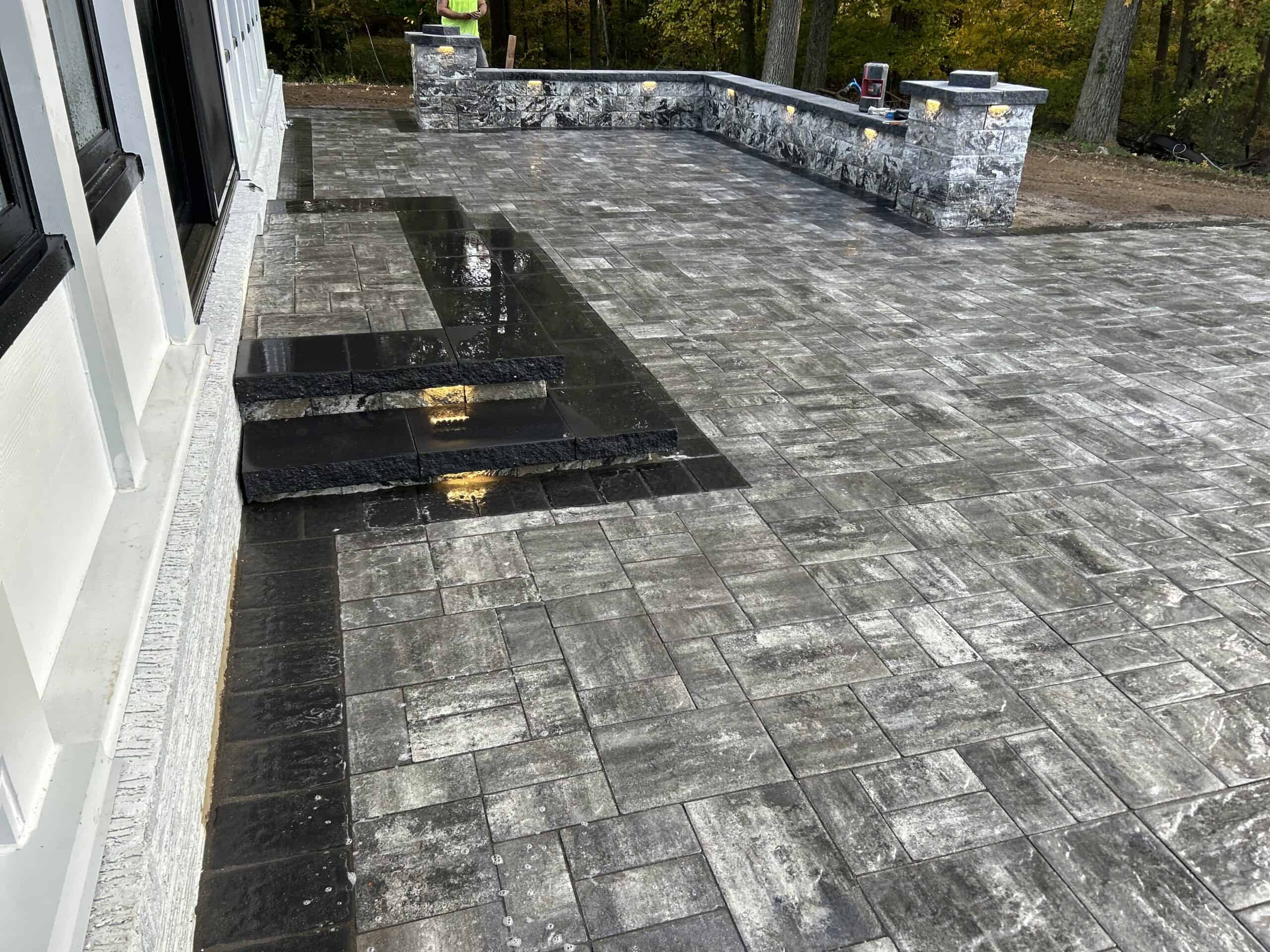 Professional patio installation with polished stone tiles by C&J Outdoor Services.