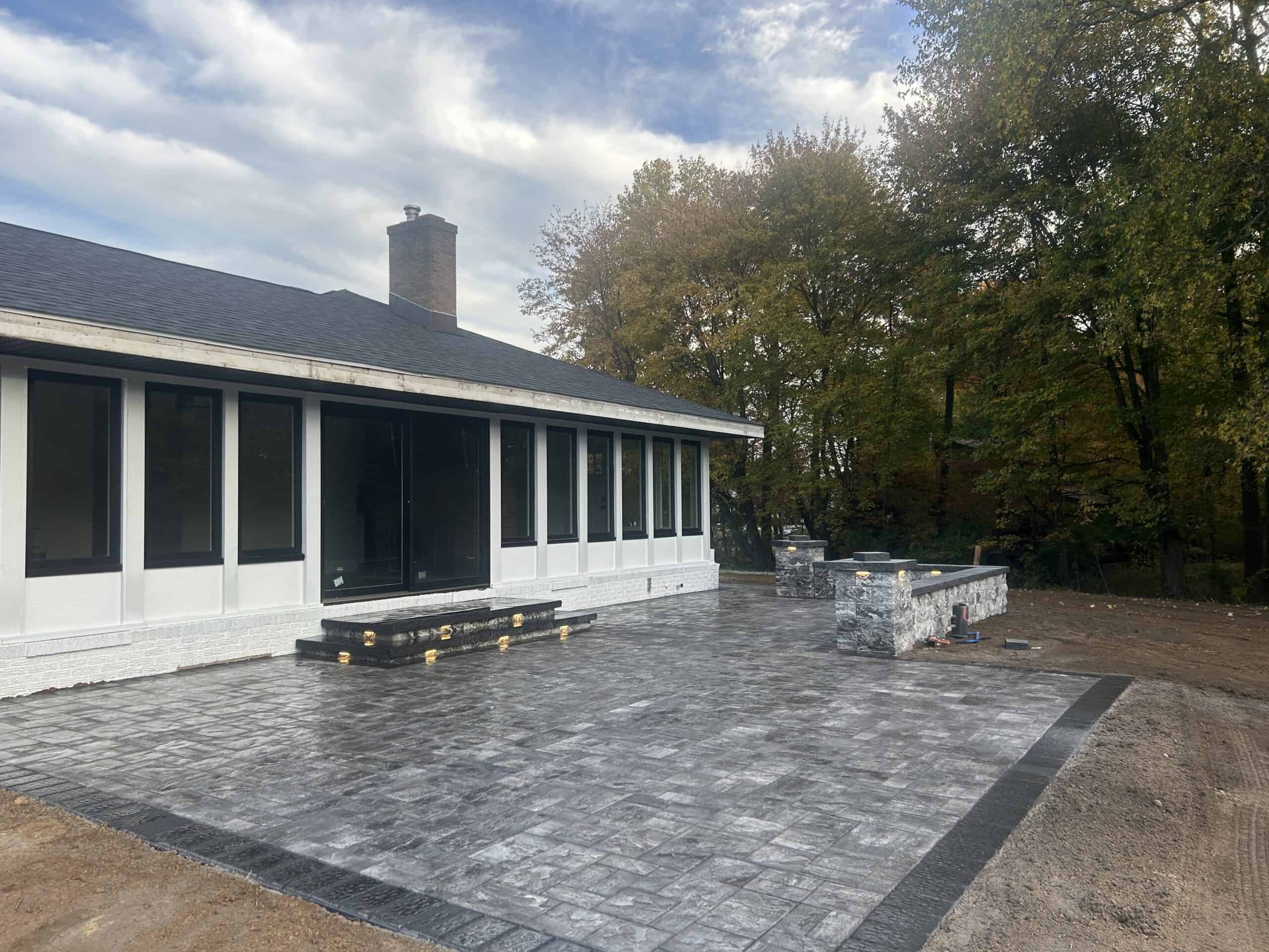Outdoor stamped concrete patio with stone features and landscaping by C&J Outdoor Services.
