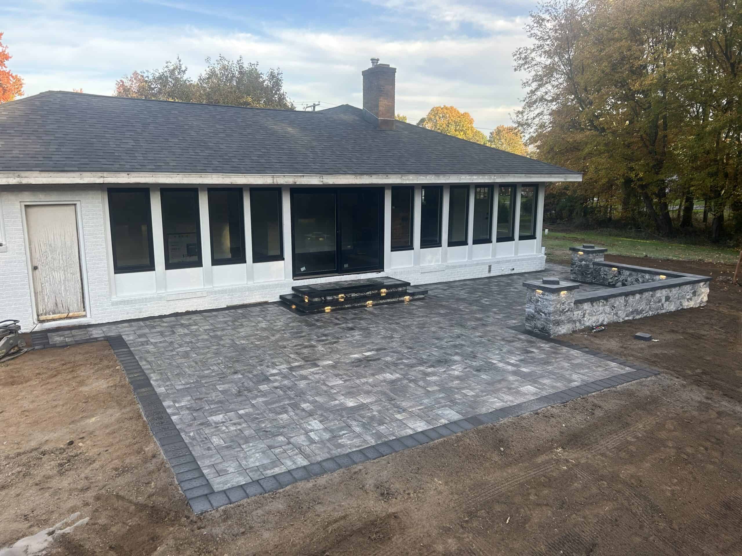 Patio with paver stones and outdoor seating area by C&J Outdoor Services.