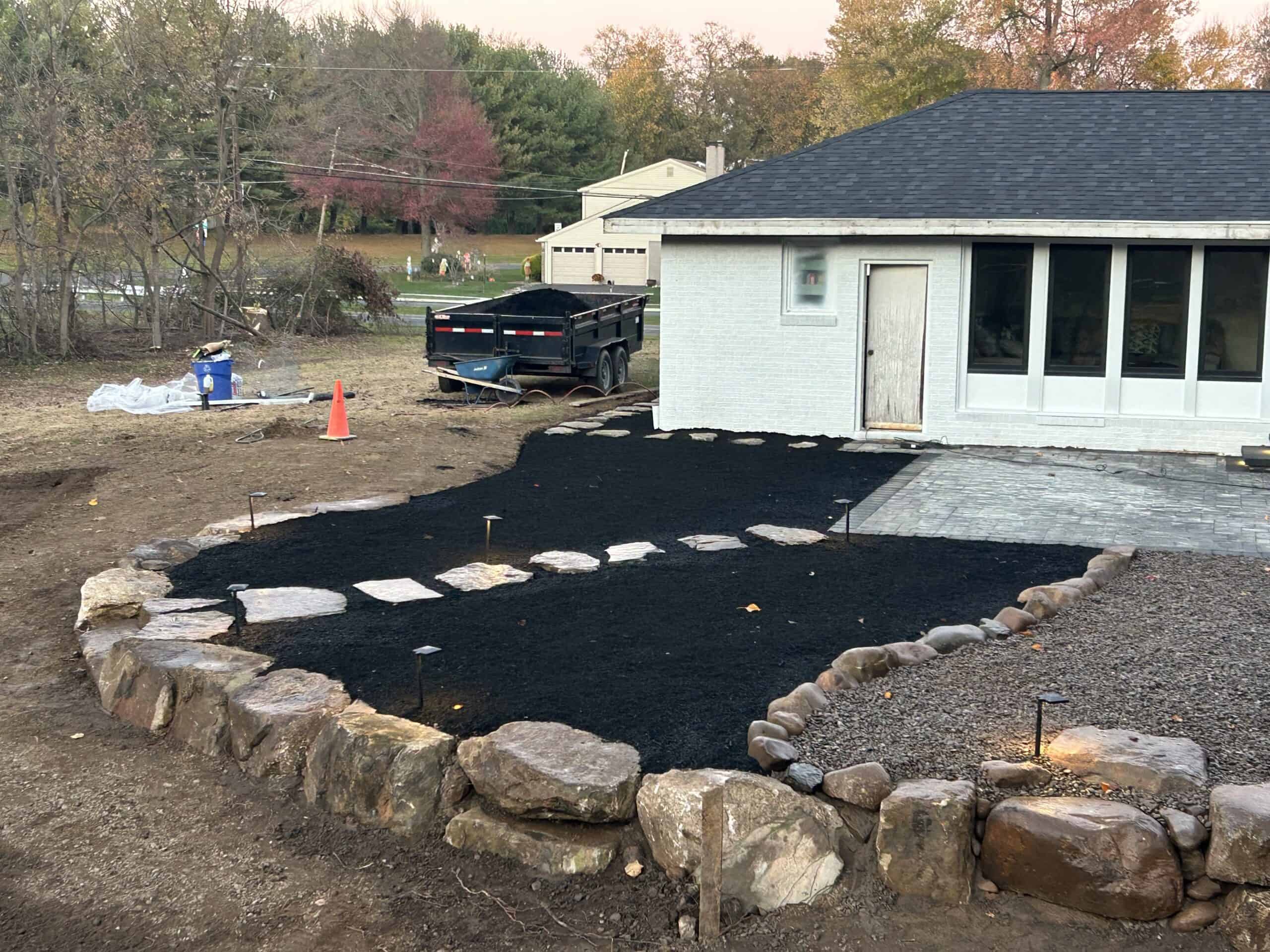 Outdoor patio with stone border and black mulch, backyard landscaping project.