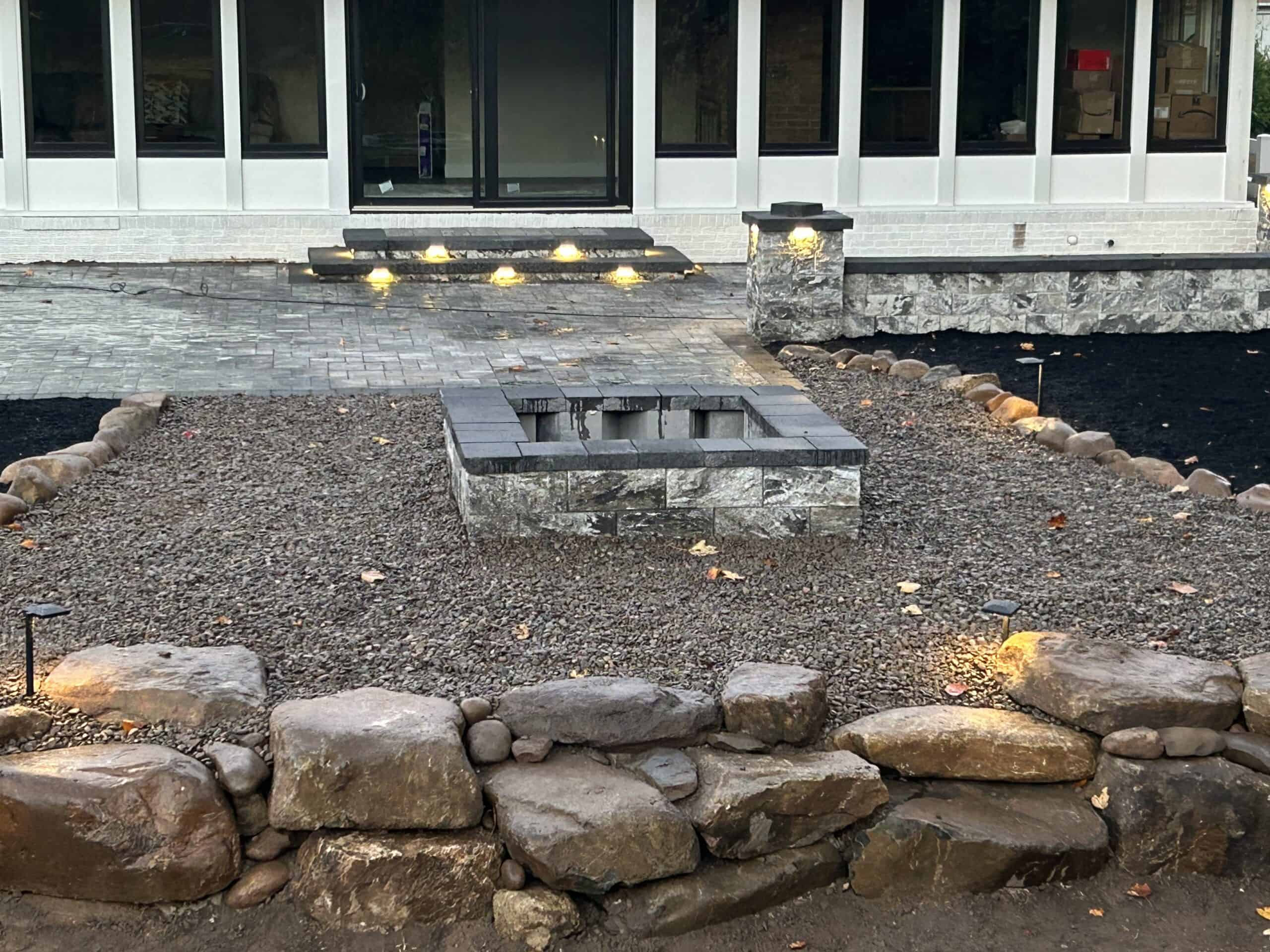Custom stone fire pit installation in backyard by C&J Outdoor Services.