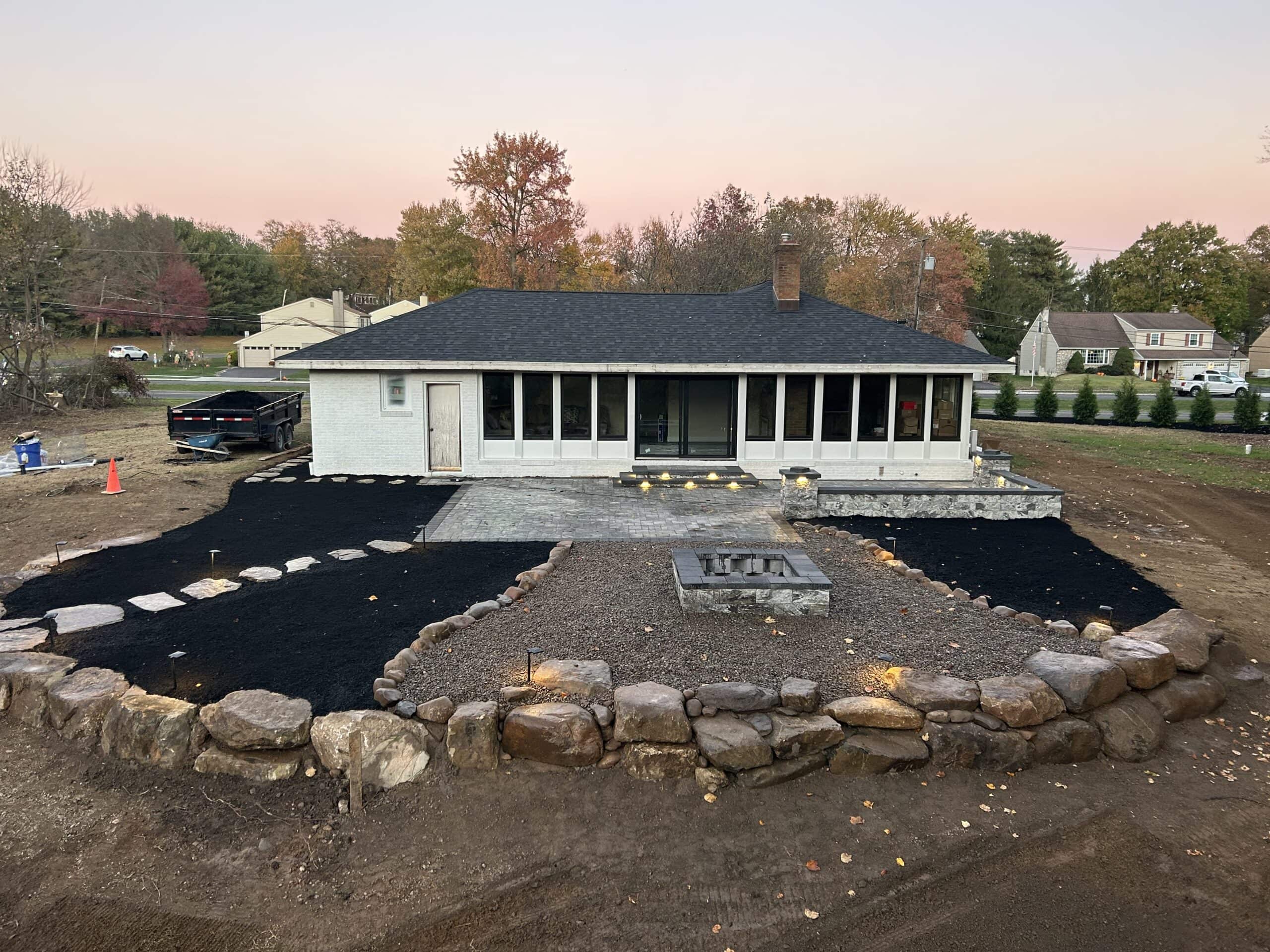 Outdoor patio installation with stone border and landscaping by C&J Outdoor Services.