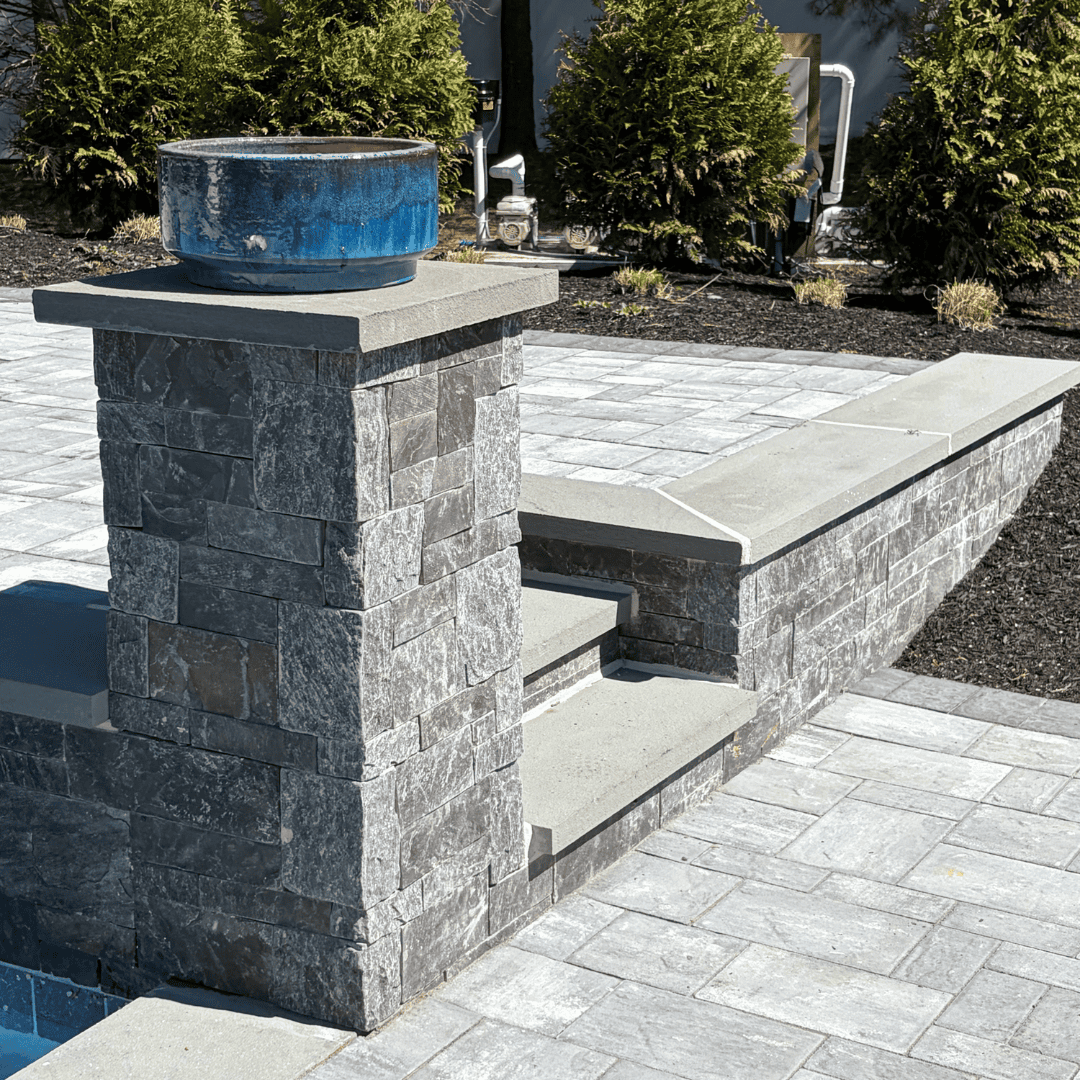 Water fountain with stone pillar and modern patio setup.