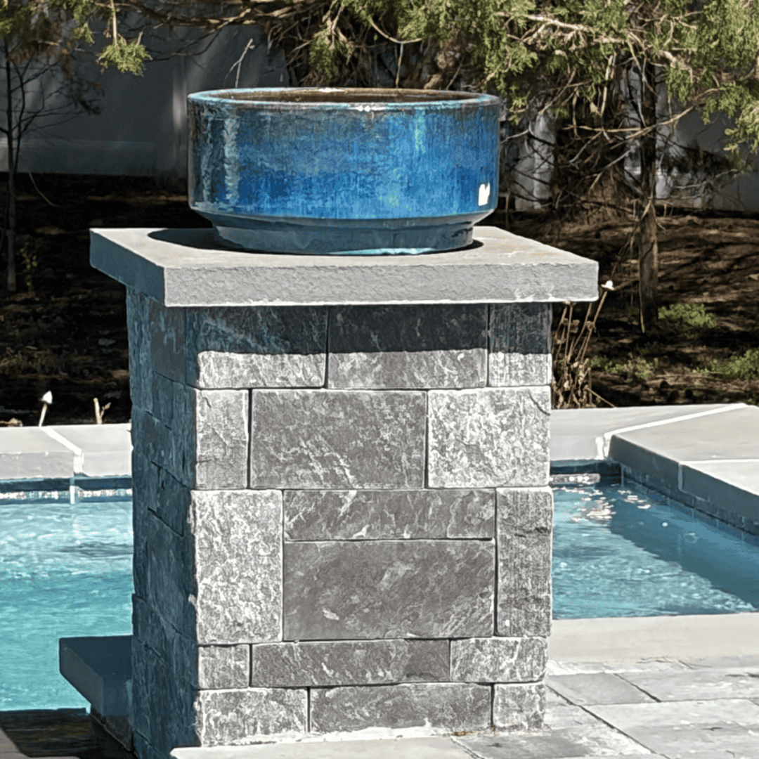 Outdoor stone fountain with blue ceramic basin for garden decor.
