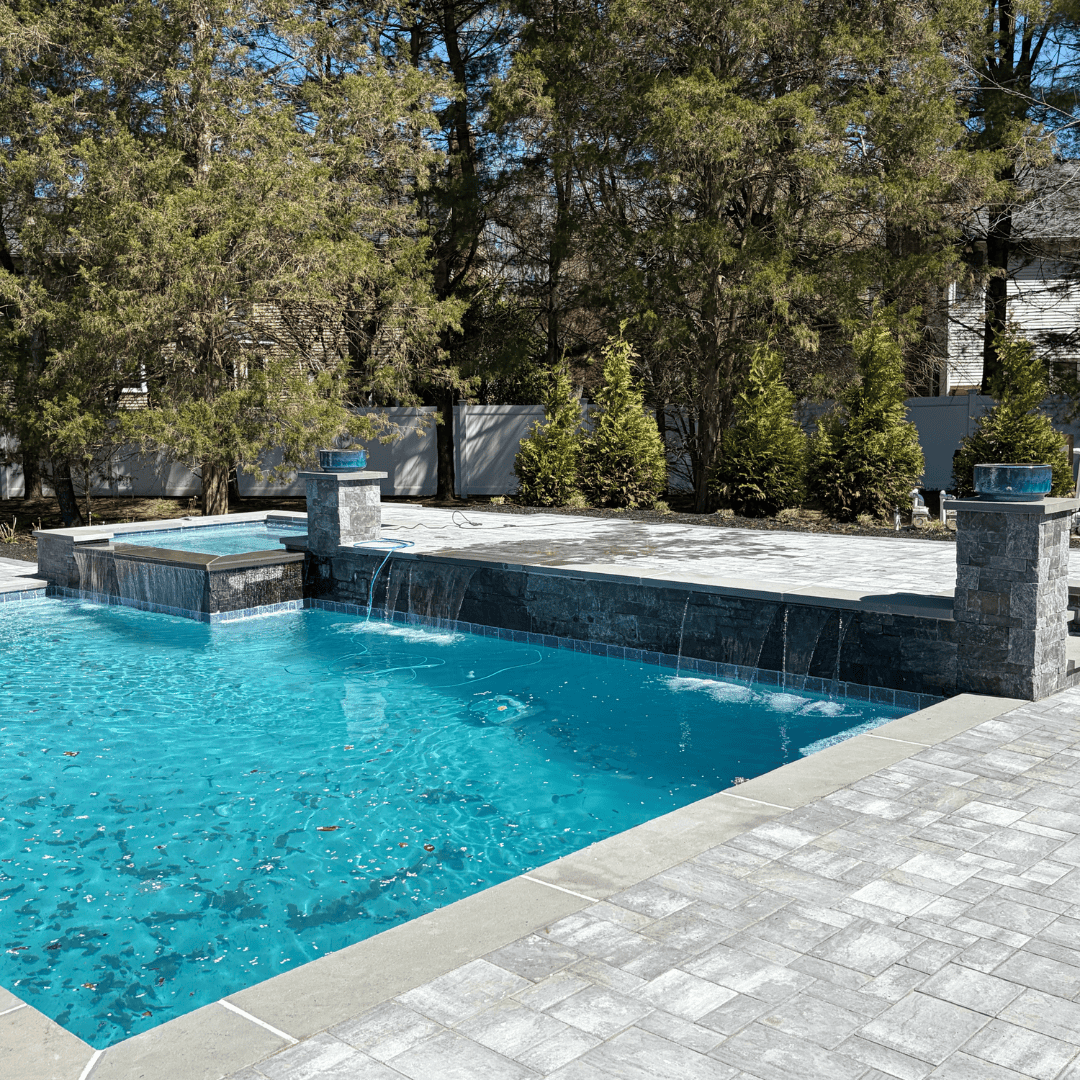 Beautiful backyard pool with waterfall feature and lush landscaping.