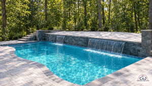 Beautiful backyard pool with waterfall feature and lush trees in the background.