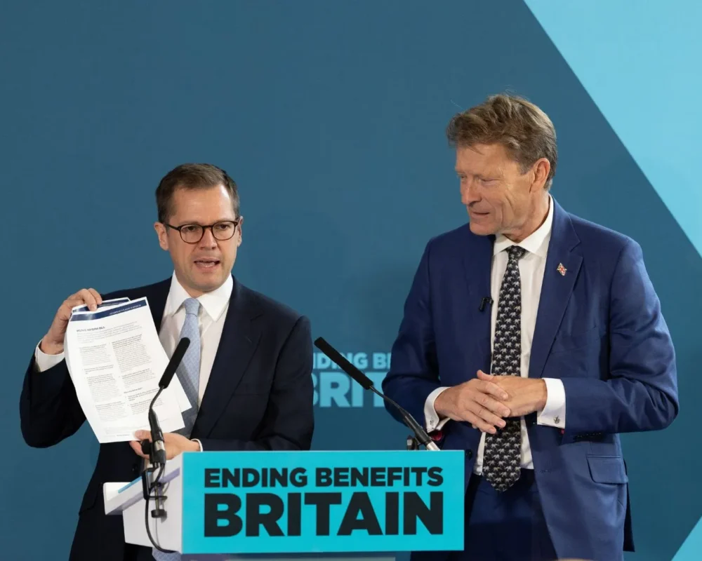 Two men discussing welfare reform on stage at a conference.