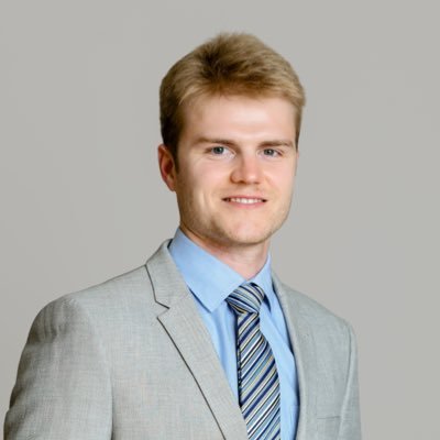 Professional young man in a light gray suit and blue shirt with striped tie.