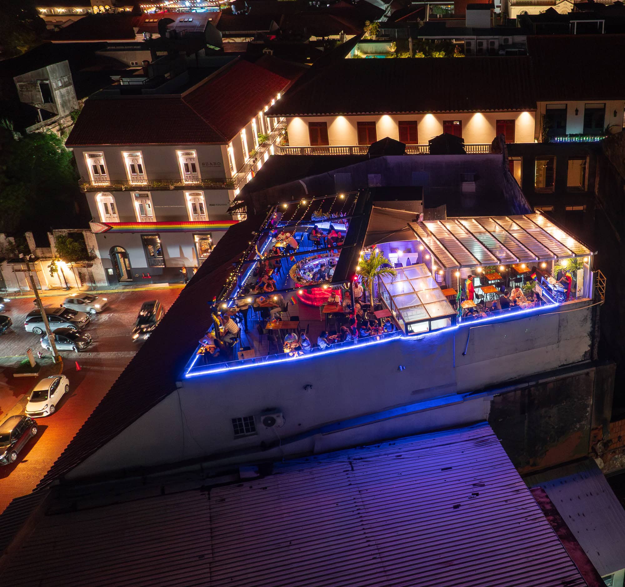 Aerial night view of Sky Rooftop Bar in Casco Viejo, Panama, glowing with string lights and a vibrant crowd above the historic district.