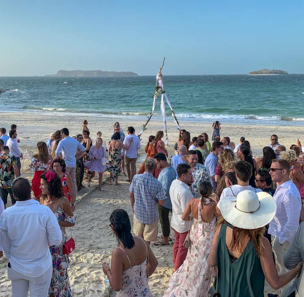 Destination wedding celebration on the beach of Contadora Island, Panama, with guests gathered by the sea.