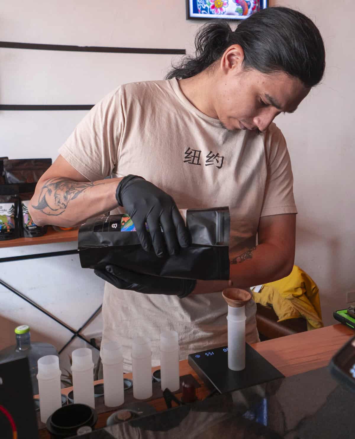 Antonio measuring coffee at Kail Tattoo Studio & Coffee Bar in Casco Viejo Panama, reflecting focus and craftsmanship.