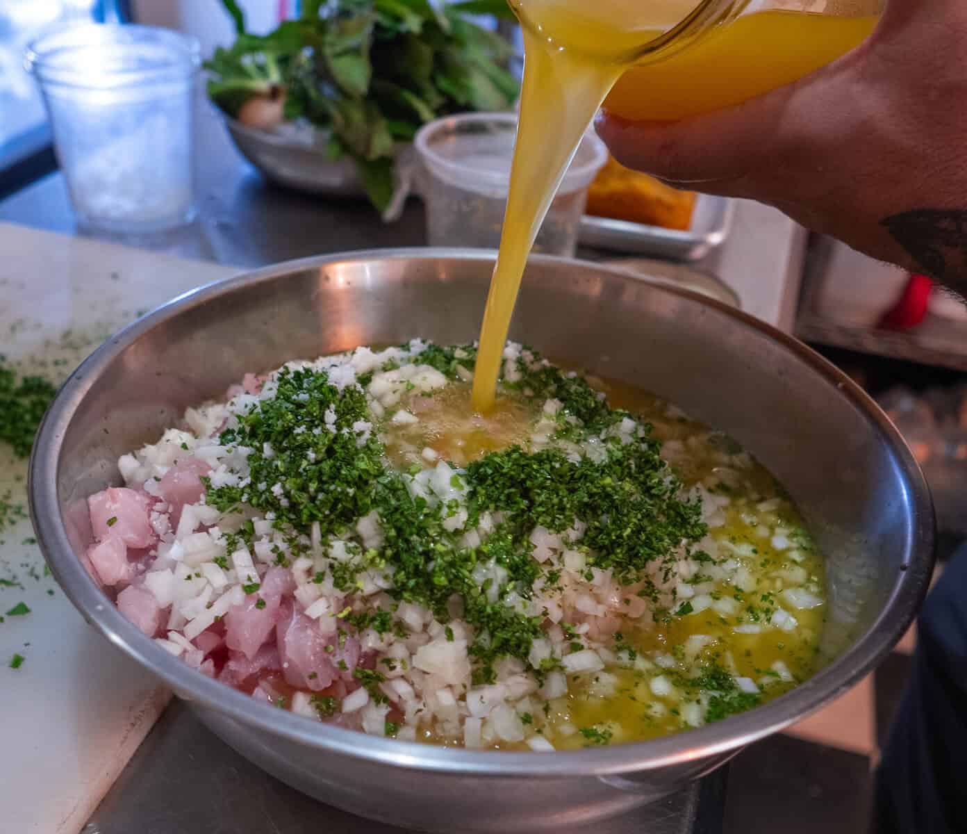 Chef Christian preparing fresh Panamanian ceviche, pouring citrus over chopped fish, onions, and herbs.