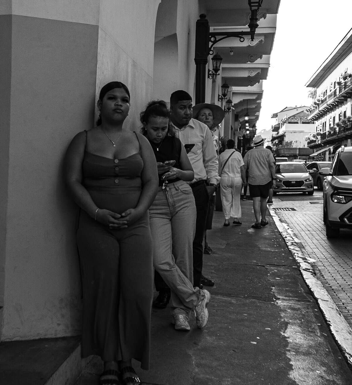 People lined up along a sidewalk in Casco Viejo waiting for transportation home