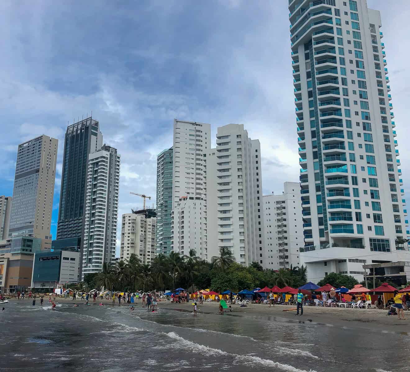 Bocagrande Beach in Cartagena with beachfront high-rises, colorful umbrellas, and visitors along the Caribbean shoreline.