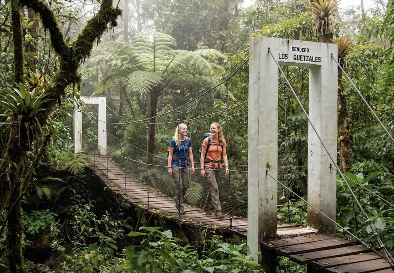 Two hikers crossing a suspension bridge on Sendero Los Quetzales near Boquete, Panama