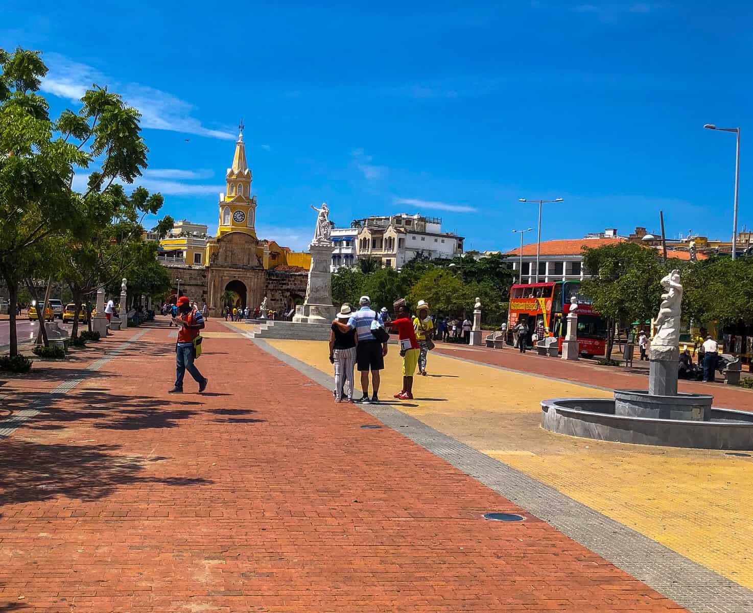Visitors walking across Plaza de la Paz toward Cartagena’s Clock Tower and historic walled city entrance.
