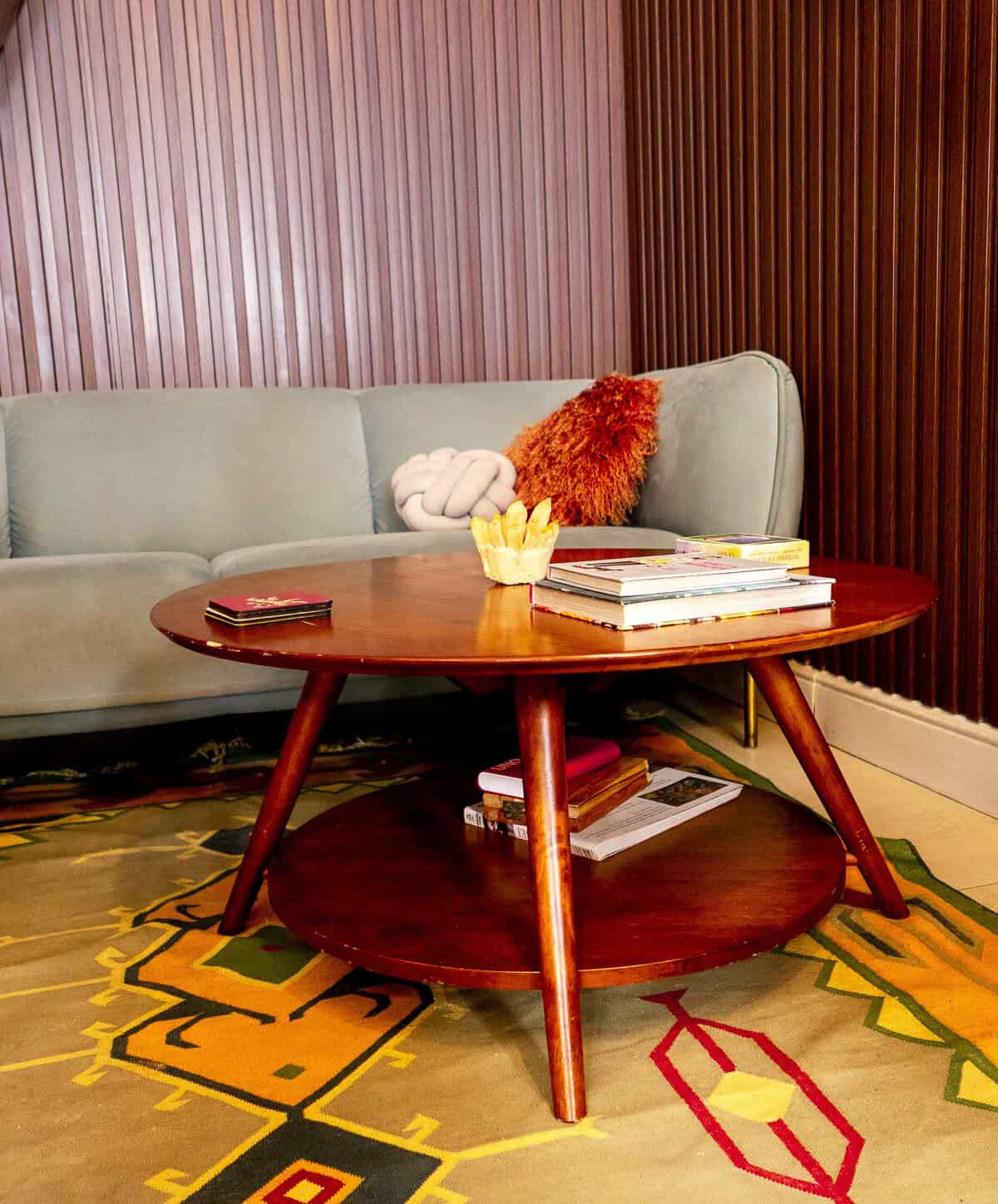 Pale green sofa and wooden coffee table with books on a colourful patterned rug inside The Vegan Shack in Casco Viejo.