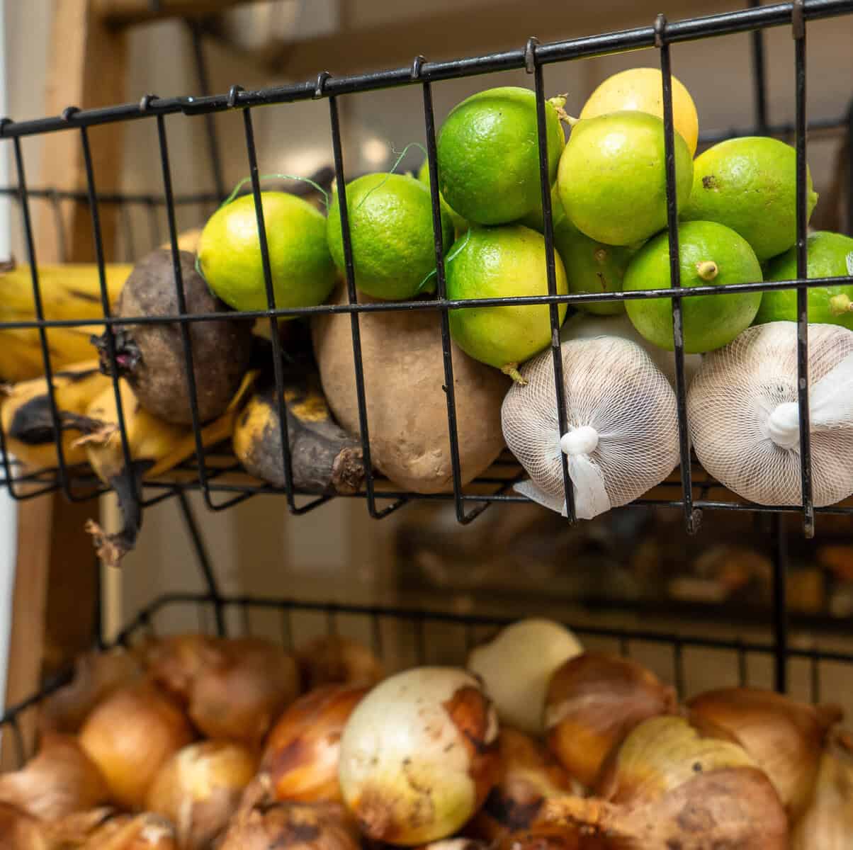 Fresh limes, garlic, bananas, root vegetables, and onions stored in baskets at Vegan Shack in Casco Viejo, Panama.