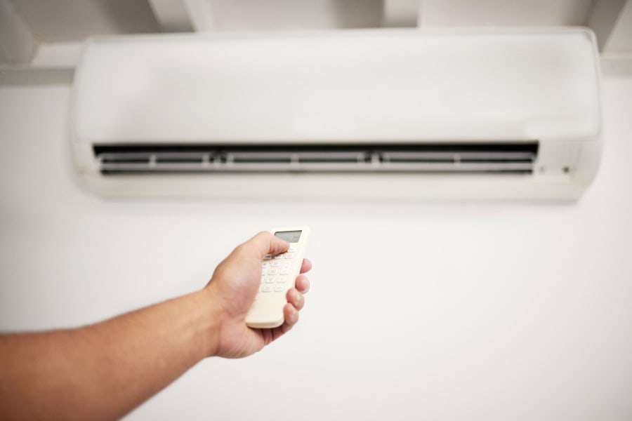 Person switching off air conditioning system at the power source before cleaning the AC filter.