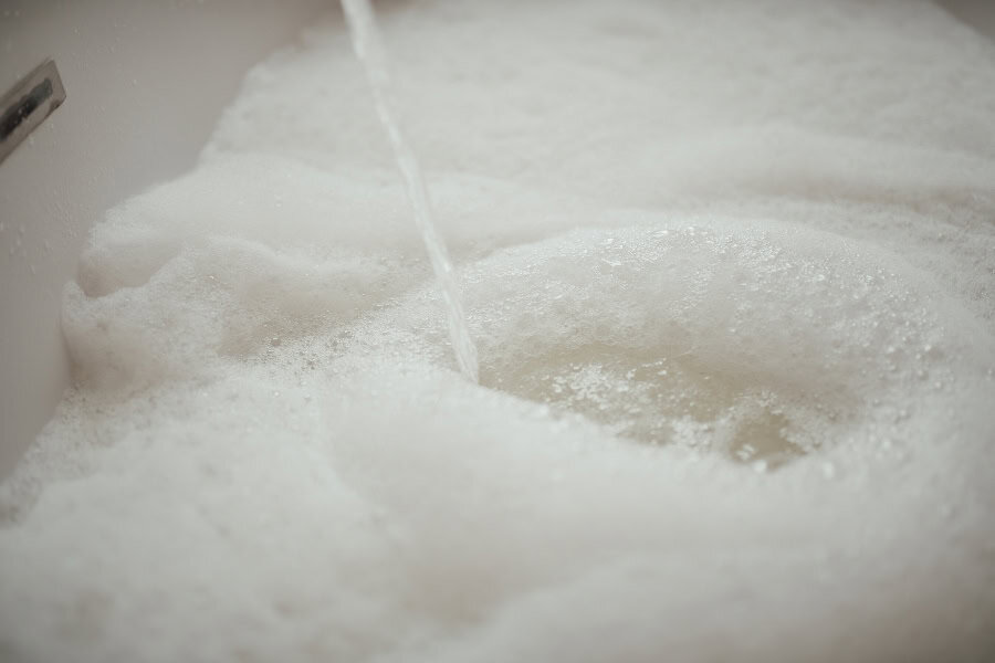 Washing air conditioner filters in warm soapy water to remove built-up dust and debris during cleaning.