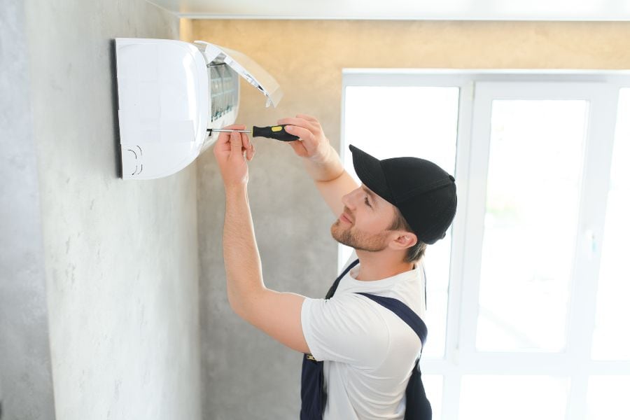 Technician inspecting air conditioner filter during service, showing when expert help is needed.