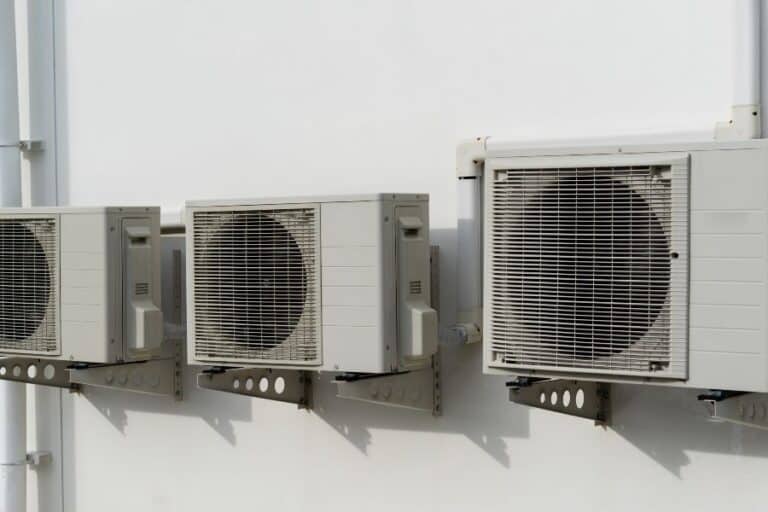 Outdoor HVAC units mounted on wall for heating, ventilation, and air conditioning.