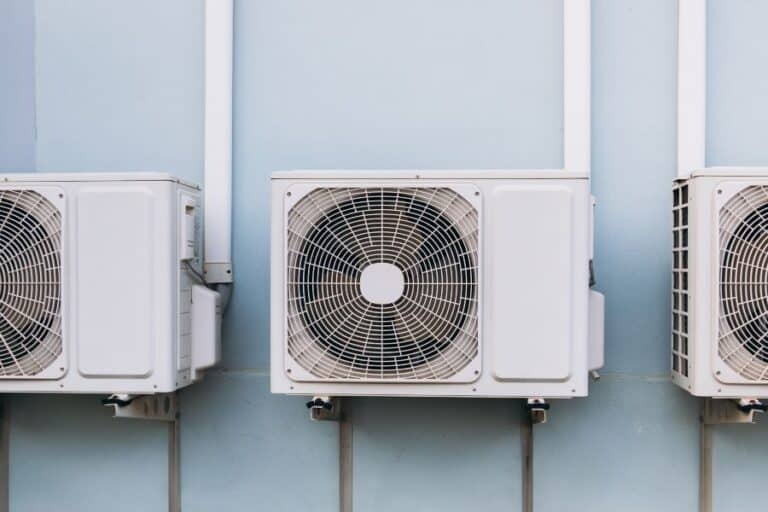 Row of three outdoor air conditioning units mounted on a wall, illustrating modern cooling technology.