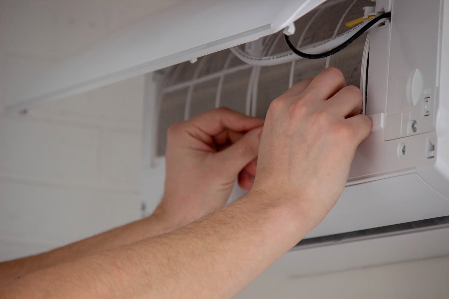 Hands accessing internal panel of a Daikin air conditioner to reset or adjust settings.