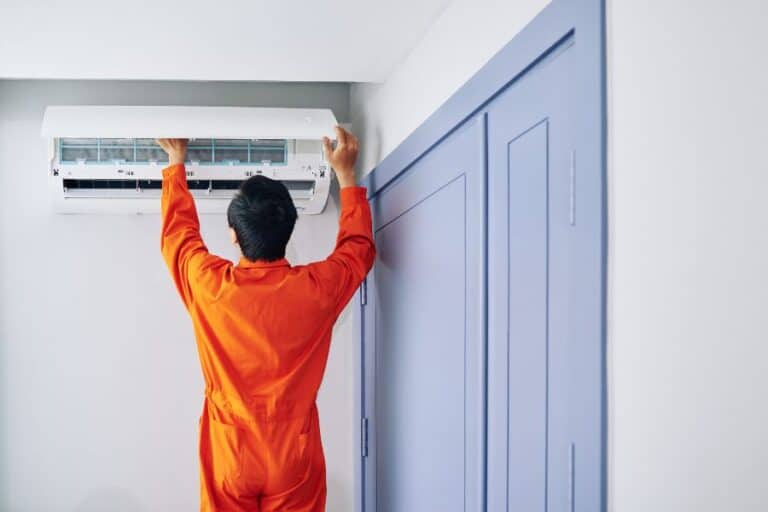 Technician installing a wall-mounted air conditioner inside a modern home.