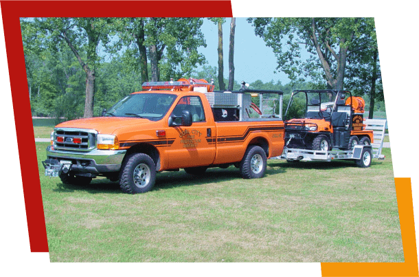 Orange utility truck towing equipment on grass