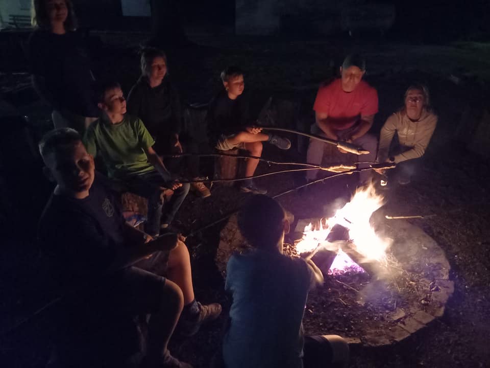 Personengruppe beim nächtlichen Lagerfeuer.