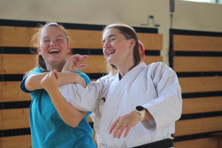 Zwei Personen üben lächelnd Judo.